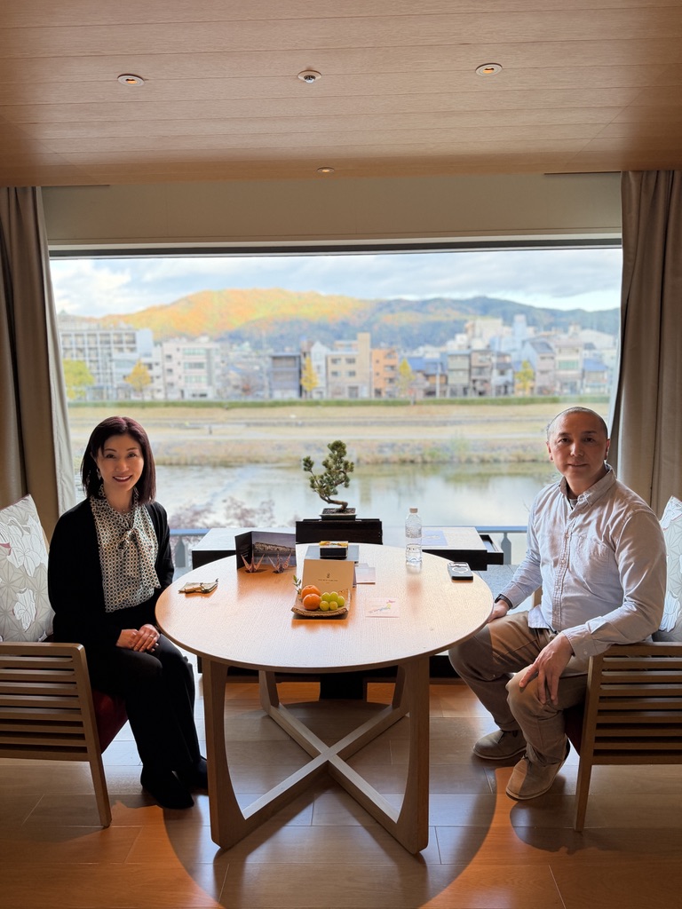 リッツカールトン京都 客室の窓際の椅子とテーブル。背景に鴨川と紅葉。